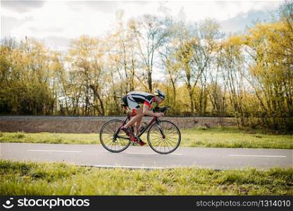 Cyclist in helmet and sportswear rides on bicycle, speed effect, side view. Workout on bike path. Cyclist rides on bicycle, speed effect, side view