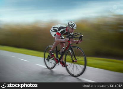 Cyclist in helmet and sportswear rides on bicycle, speed effect, side view. Cyclist rides on bicycle, speed effect, side view