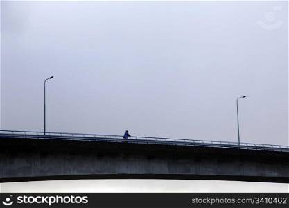 cyclist on bridge and threatening sky