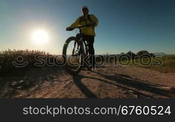Cyclist riding bicycle along a mountain path in early morning