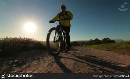 Cyclist riding bicycle along a mountain path in early morning