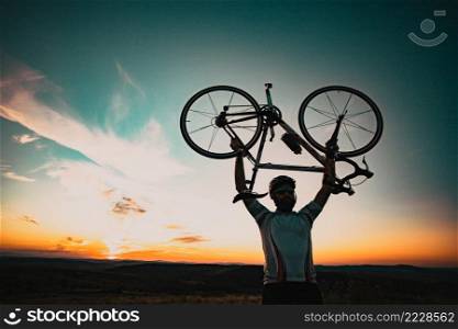 cyclist silhoutte with bicycle raised to sky race and victory concept