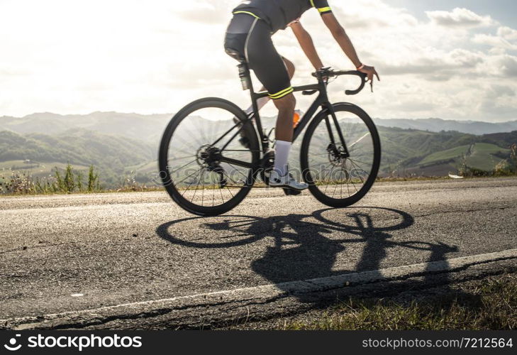 Cyclist sports on road. Sun Rays and shadows from the bike on the road. Outdoor cycling.
