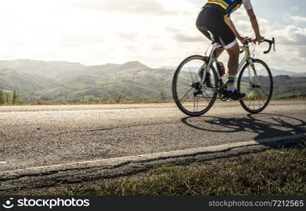 Cyclist sports on road. Sun Rays and shadows from the bike on the road. Outdoor cycling.