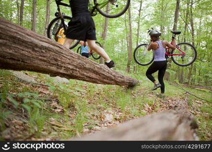 Cyclists carrying bikes in forest