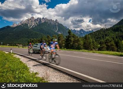 Cyclists riding a bicycle on the road in the background the Dolomites Alps Italy. Warning - authentic shooting there is a motion blur.
