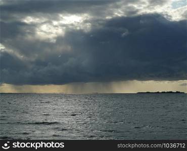 cyclone, a huge black cloud pours rain on the sea