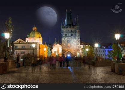 Czech Republic. Prague. Night on the Charles bridge and the moon. Many unrecognizable people. Tourists on the Charles Bridge at Night