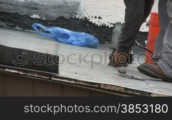 Dachdecker verlegt erste Schicht auf einem zukuenftigen Schindeldach - roofer is installing tin caps on base sheet