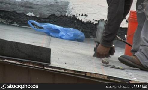 Dachdecker verlegt erste Schicht auf einem zukuenftigen Schindeldach - roofer is installing tin caps on base sheet