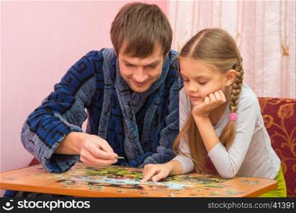 Dad and daughter enthusiastically collect picture of puzzles