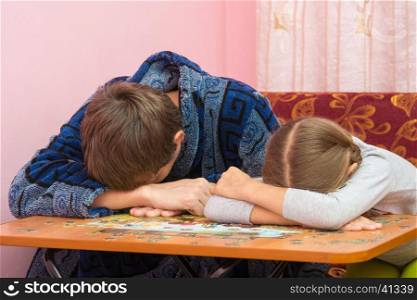 Dad and daughter fell asleep at the table collecting picture of puzzles