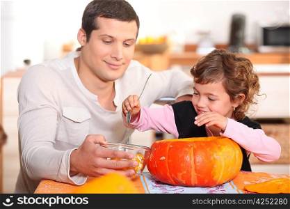 Dad and daughter hollowing out a pumpkin