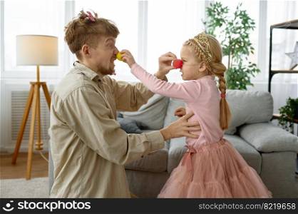 Dad and daughter wearing clown nose having fun together, happy family portrait. Dad and daughter wearing clown nose having fun