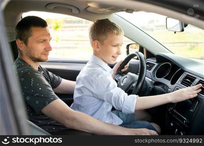 Dad and son in the front seat of a car driving a black car. The boy holds the steering wheel. A father teaches his son to drive a car. Presses the button. Dad and happy son in the front seat of a car driving a car. The boy holds the steering wheel.