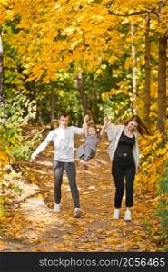 Dad, mom and daughter are walking in the autumn forest.. Autumn walk of a young family in the forest 3371.
