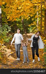 Dad, mom and daughter are walking in the autumn forest.. Autumn walk of a young family in the forest 3373.