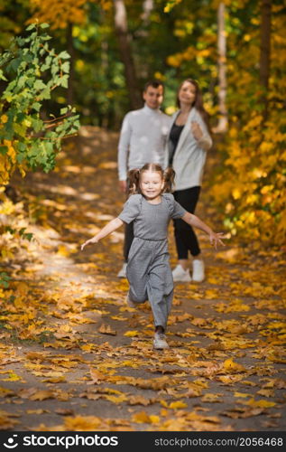 Dad, mom and daughter are walking in the autumn forest.. Autumn walk of a young family in the forest 3374.