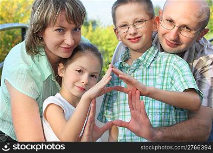 dad, mom, son and daughter is using their hands to represent home. focus on son&acute;s face.