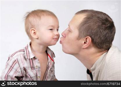 Daddy kisses his little son on the white background