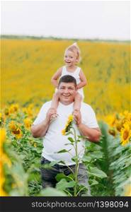 Daddy&rsquo;s carrying a baby daughter on his shoulders in the field of sunflowers. The concept of summer holiday. Father&rsquo;s, baby&rsquo;s day. Spending time together. Family look. Daddy&rsquo;s carrying a baby daughter on his shoulders in the field of sunflowers. The concept of summer holiday. Father&rsquo;s, baby&rsquo;s day. Spending time together. Family look.