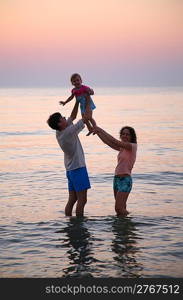 Daddy with mummy and child in sea on sunset