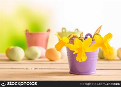 Daffodils in a purple flowerpot with easter eggs in the background
