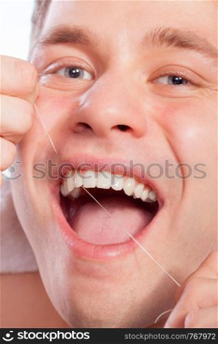 Daily health care. Young man cleaning flossing his white teeth with dental floss