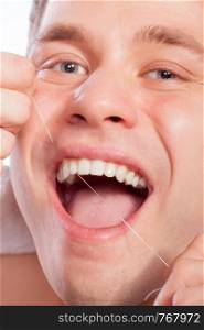 Daily health care. Young man cleaning flossing his white teeth with dental floss