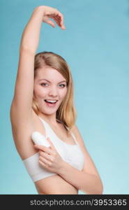 Daily skin care and hygiene. Girl applying stick deodorant in armpit. Young woman putting antiperspirant in underarms on blue