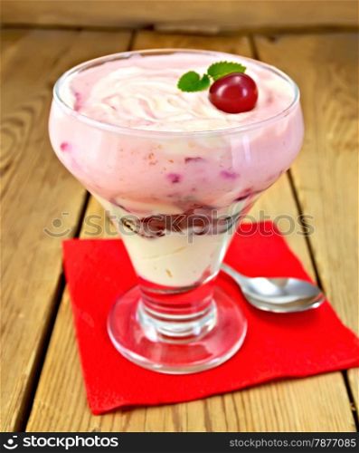 Dairy dessert with cherry, chocolate biscuit and curd, spoon, cherries on a red paper napkin on a wooden boards background