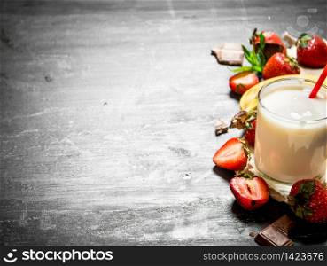 Dairy dessert with strawberries and banana. On the black wooden table.. Dairy dessert with strawberries and banana.