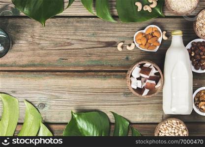 Dairy free milk substitute drink and ingredients on od wood background, flat lay. Vegan, vegetarian, clean eating concept
