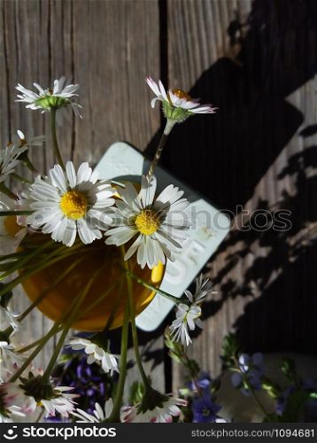 daisy fresh wild flowers in yellow ceramic vase, on wooden veranda background. Still life in rustic style. Close up Top view. Summer in garden, countryside lifestyle concept