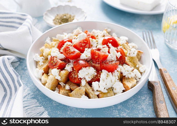 Dakos or koukouvagia salad. Classic recipe Cretan barley rusk salad with fresh tomato, mizithra cheese and oregano. Traditional mediterranean Greek cuisine. Healthy food, diet