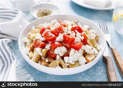 Dakos or koukouvagia salad. Classic recipe Cretan barley rusk salad with fresh tomato, mizithra cheese and oregano. Traditional mediterranean Greek cuisine. Healthy food, diet