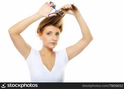 Damaged dry hair splitting ends. Young blonde woman cutting her hair with scissors - unhappy expression, isolated on white background