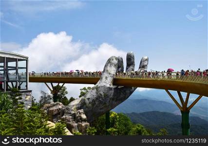 Danang, Vietnam - April 6, 2019: The Golden Bridge is lifted by two giant hands in the tourist resort on Ba Na Hill in Danang, Vietnam. Ba Na Hill mountain resort is a favorite destination for tourists. Danang, Vietnam - April 6, 2019: The Golden Bridge is lifted by two giant hands in the tourist resort on Ba Na Hill in Danang, Vietnam.
