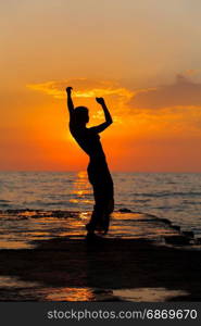 Dance at sunset. Silhouette of a girl dancing on the background of sea sunset