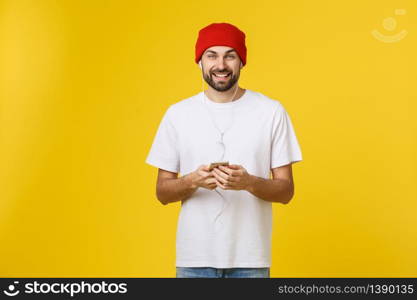 Dance. Handsome young stylish man in headphones holding mobile phone and dancing while standing against yellow background.. Dance. Handsome young stylish man in headphones holding mobile phone and dancing while standing against yellow background