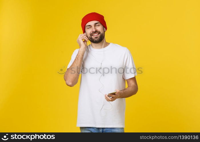 Dance. Handsome young stylish man in headphones holding mobile phone and dancing while standing against yellow background.. Dance. Handsome young stylish man in headphones holding mobile phone and dancing while standing against yellow background