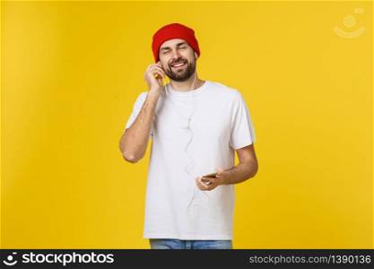 Dance. Handsome young stylish man in headphones holding mobile phone and dancing while standing against yellow background.. Dance. Handsome young stylish man in headphones holding mobile phone and dancing while standing against yellow background