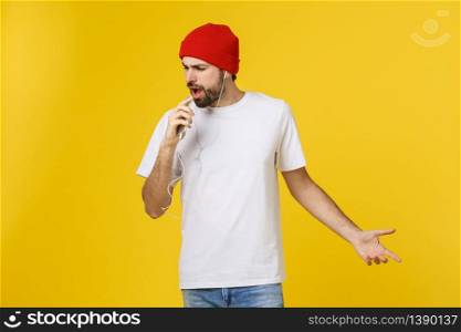 Dance. Handsome young stylish man in headphones holding mobile phone and dancing while standing against yellow background.. Dance. Handsome young stylish man in headphones holding mobile phone and dancing while standing against yellow background