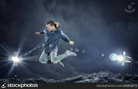 Dance with me. Modern style male dancer jumping in lights of spotlight