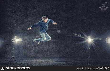 Dance with me. Modern style male dancer jumping in lights of spotlight