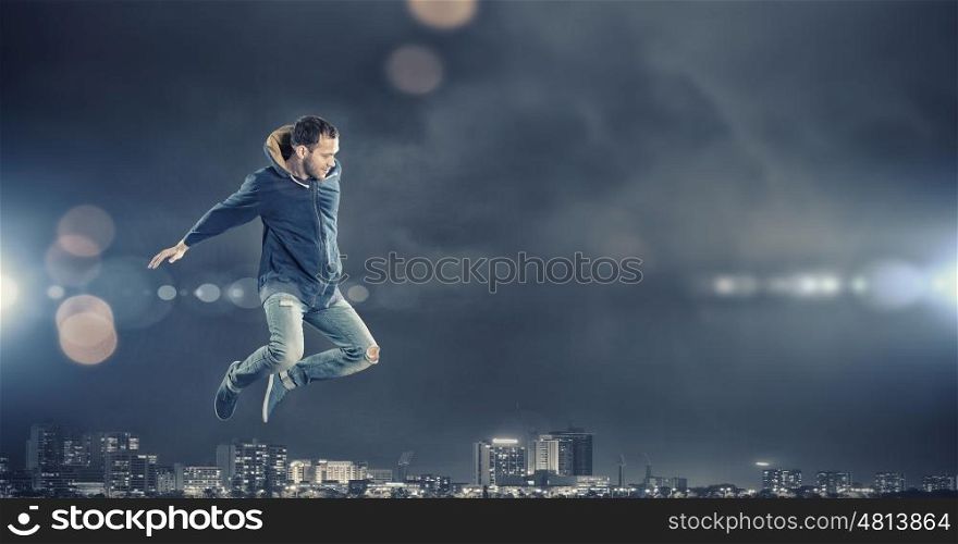 Dance with me. Modern style male dancer jumping in lights of spotlight