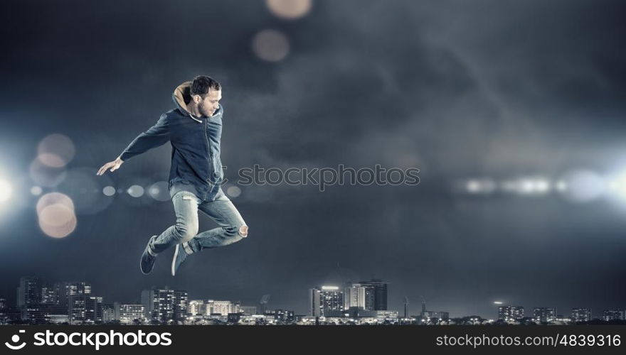 Dance with me. Modern style male dancer jumping in lights of spotlight