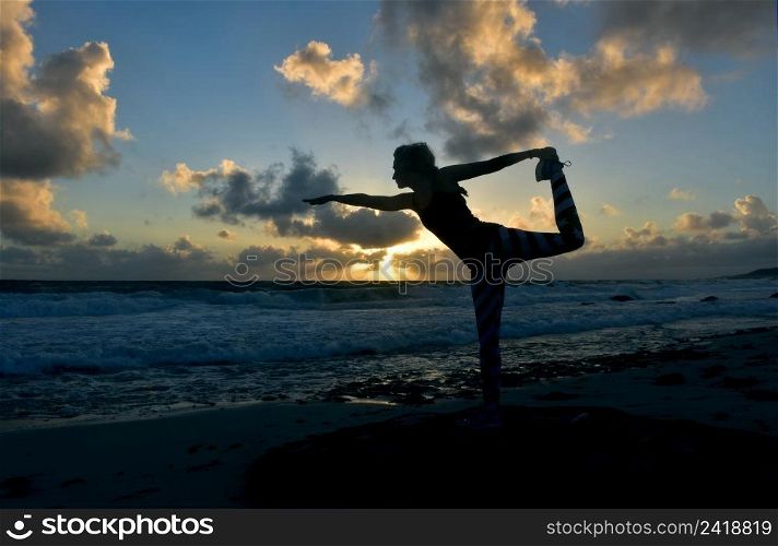Dancer balance pose silhouetted at sunrise along the coast of Aruba.