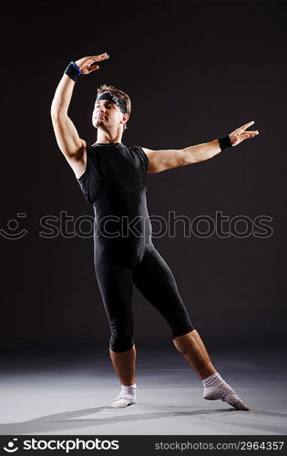 Dancer dancing dances in dark studio