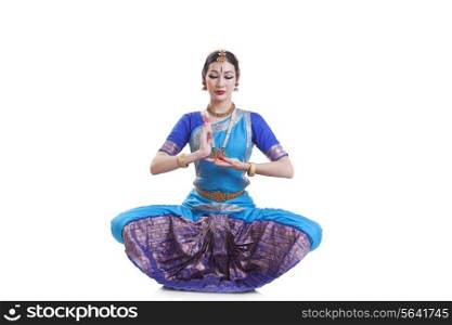 Dancer gesturing while performing Bharatanatyam against white background